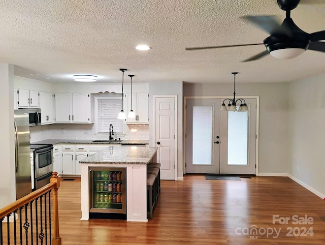 kitchen featuring decorative light fixtures, wood-type flooring, white cabinetry, and stainless steel appliances