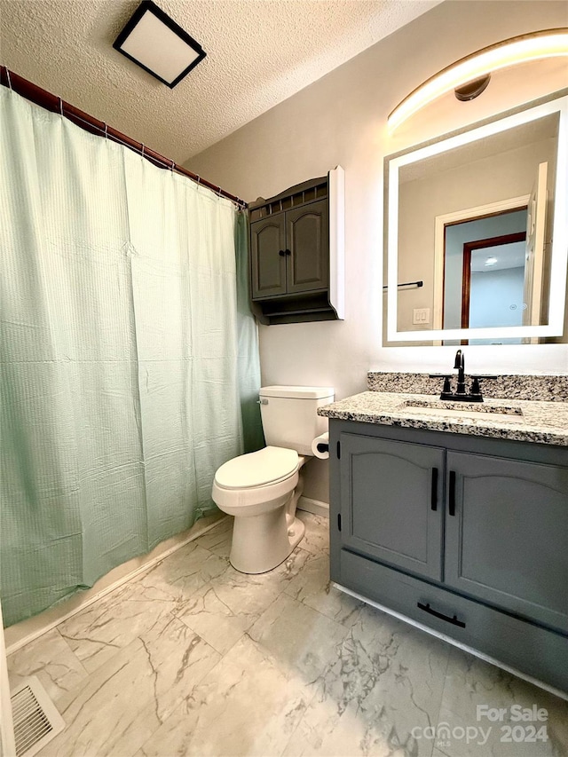 bathroom with vanity, a textured ceiling, and toilet