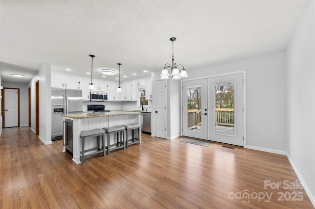 kitchen with a center island, decorative light fixtures, a breakfast bar area, stainless steel appliances, and white cabinetry