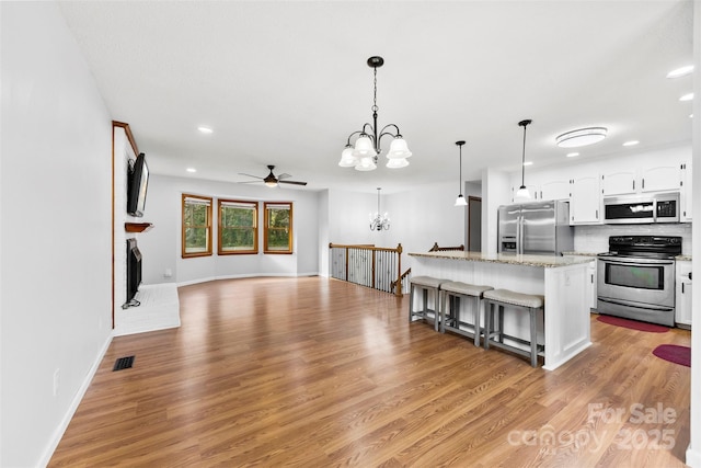 kitchen with a breakfast bar, visible vents, white cabinetry, open floor plan, and appliances with stainless steel finishes