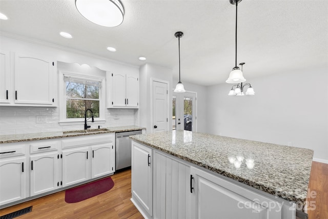 kitchen featuring a sink, white cabinetry, pendant lighting, and stainless steel dishwasher