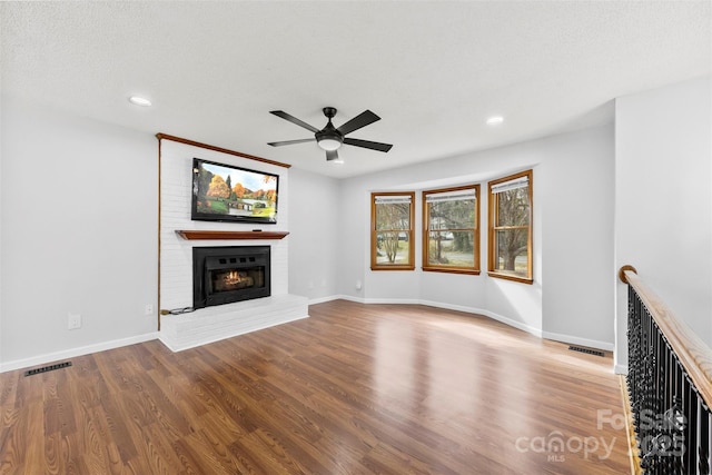 unfurnished living room with baseboards, visible vents, a ceiling fan, light wood-type flooring, and a fireplace