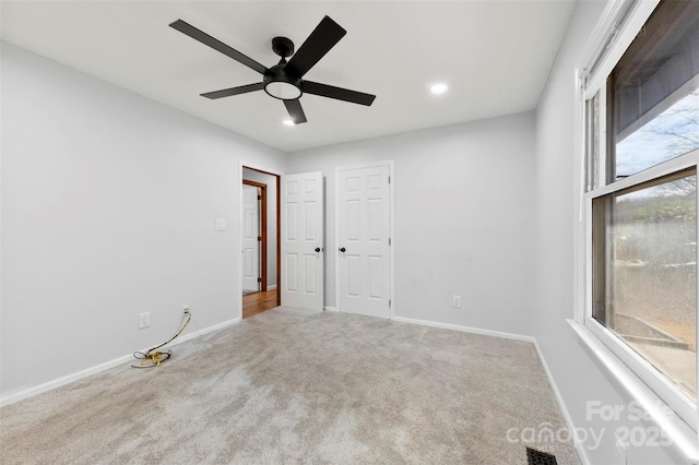 spare room featuring light carpet, ceiling fan, visible vents, and baseboards