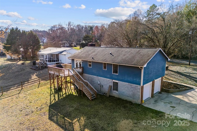 rear view of house with roof with shingles, concrete driveway, stairway, an attached garage, and a deck