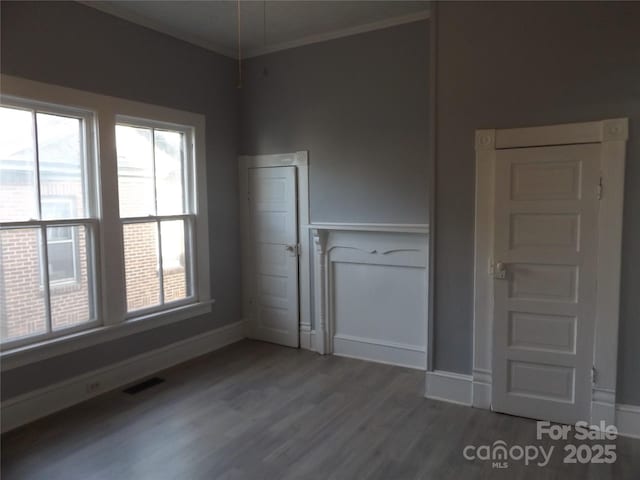 empty room with hardwood / wood-style floors and ornamental molding