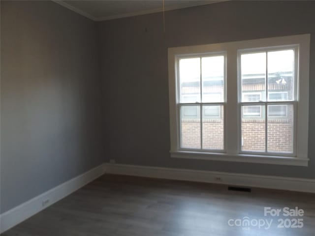 spare room featuring ornamental molding and dark wood-type flooring