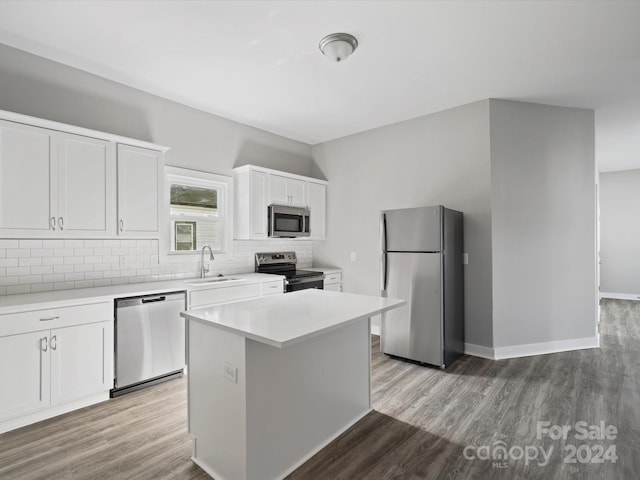 kitchen with sink, light hardwood / wood-style flooring, appliances with stainless steel finishes, a kitchen island, and white cabinetry