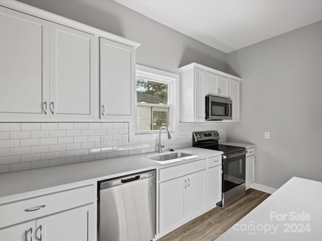 kitchen with dark wood-type flooring, sink, decorative backsplash, appliances with stainless steel finishes, and white cabinetry