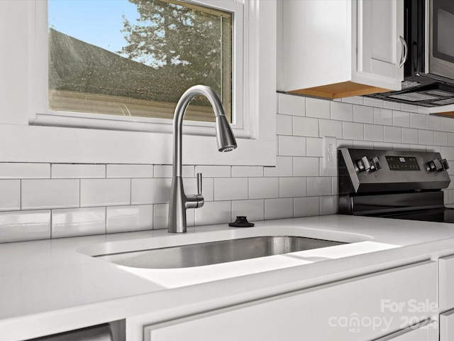 details with backsplash, black / electric stove, white cabinetry, and sink