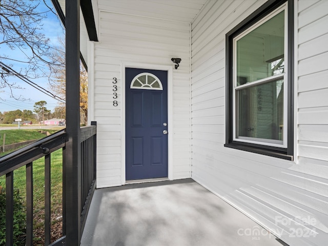 view of exterior entry with a lawn and a porch