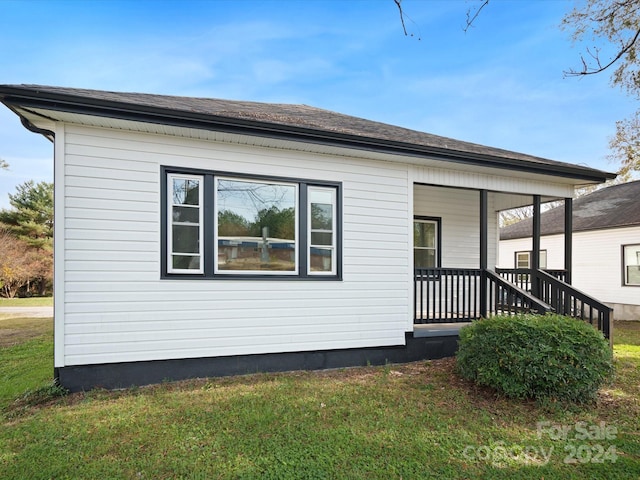 view of side of home with a yard and covered porch