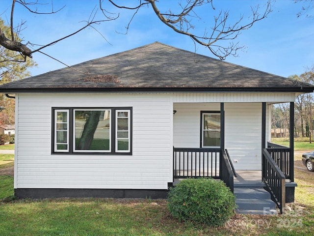 exterior space featuring covered porch and a yard