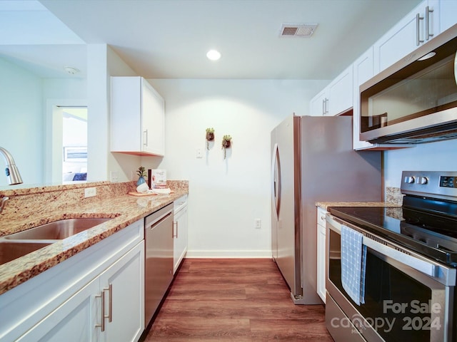 kitchen with white cabinetry, sink, dark wood-type flooring, light stone counters, and appliances with stainless steel finishes