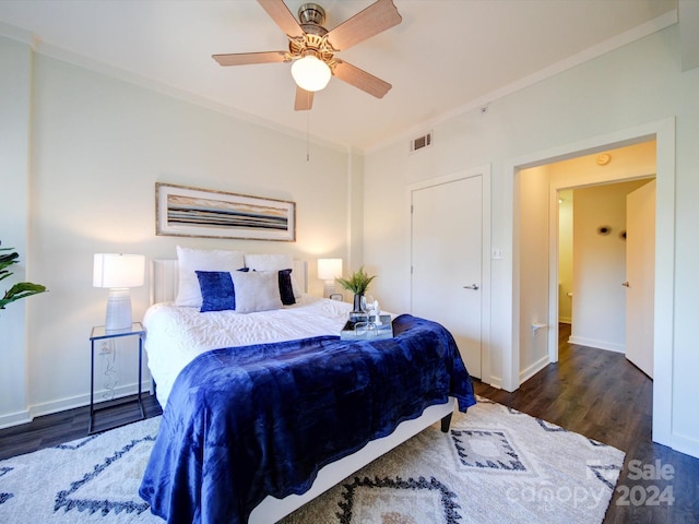 bedroom with ceiling fan, dark hardwood / wood-style floors, and ornamental molding