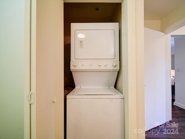 clothes washing area featuring dark hardwood / wood-style floors and stacked washing maching and dryer