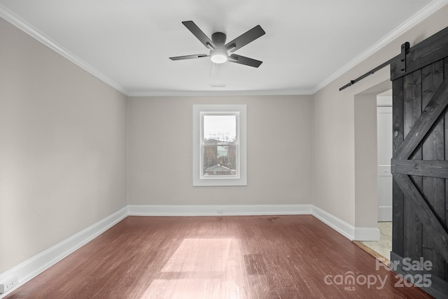 unfurnished room featuring ceiling fan, a barn door, wood-type flooring, and ornamental molding