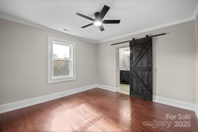 unfurnished living room featuring ceiling fan, crown molding, a barn door, and hardwood / wood-style floors