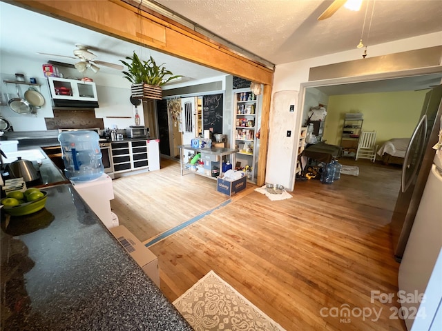 living room featuring ceiling fan, wood-type flooring, and a textured ceiling