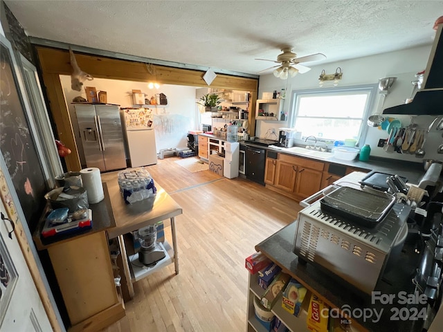 kitchen featuring sink, black dishwasher, light hardwood / wood-style flooring, stainless steel fridge, and a textured ceiling