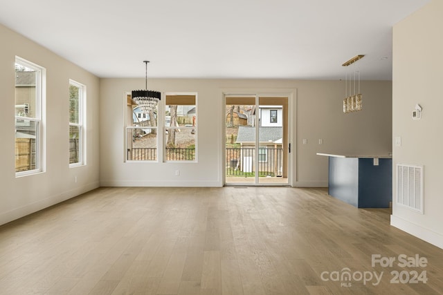 spare room featuring light hardwood / wood-style floors and a notable chandelier