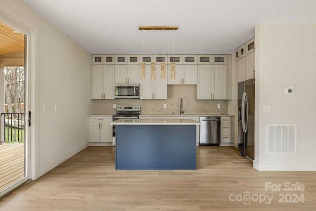 kitchen with white cabinets, pendant lighting, stainless steel appliances, and light hardwood / wood-style floors