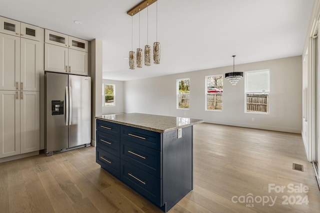 kitchen with a center island, hanging light fixtures, stainless steel fridge, light hardwood / wood-style floors, and white cabinetry