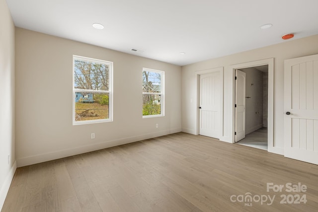 unfurnished bedroom featuring connected bathroom and light hardwood / wood-style flooring