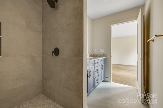 bathroom with hardwood / wood-style floors, vanity, and a tile shower