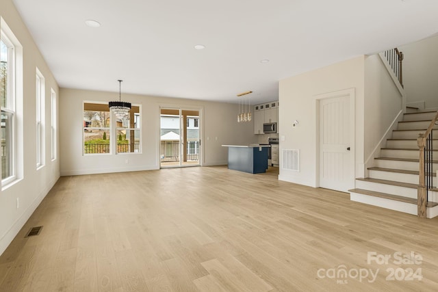 unfurnished living room with light hardwood / wood-style flooring and an inviting chandelier