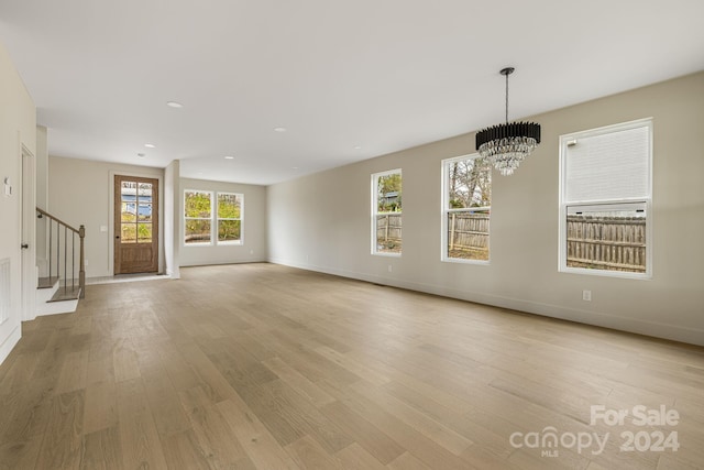 unfurnished living room with a chandelier and light wood-type flooring