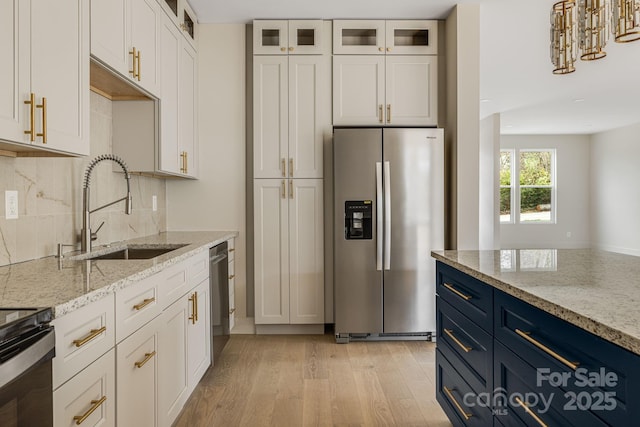 65 Bellevue Rd Unit 3, Asheville, NC 28803 - kitchen with appliances with stainless steel finishes, a sink, light wood-type flooring, tasteful backsplash, and blue cabinetry