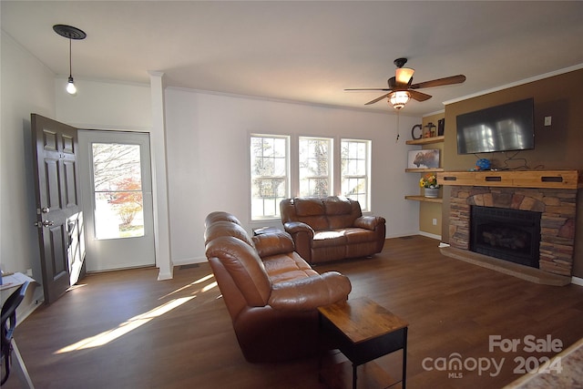 living room featuring a stone fireplace, crown molding, ceiling fan, and dark wood-type flooring