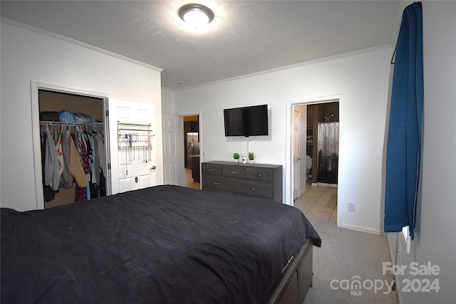 bedroom featuring a walk in closet, crown molding, connected bathroom, light colored carpet, and a closet