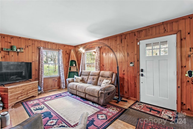 living room with light hardwood / wood-style floors, ornamental molding, and wooden walls