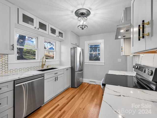 kitchen featuring sink, stainless steel appliances, backsplash, decorative light fixtures, and white cabinets