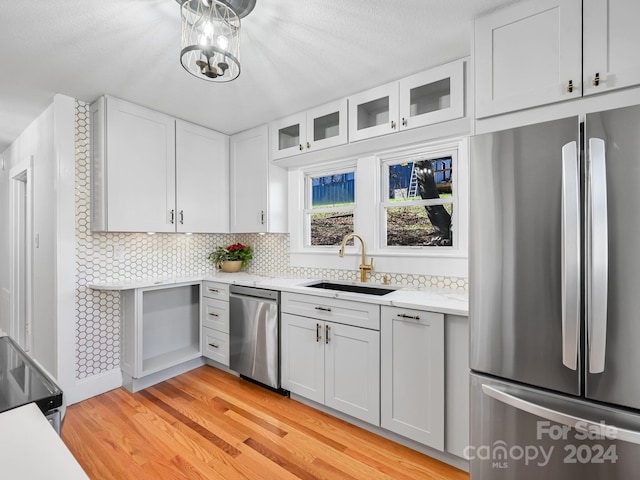 kitchen with decorative backsplash, appliances with stainless steel finishes, sink, light hardwood / wood-style flooring, and white cabinetry