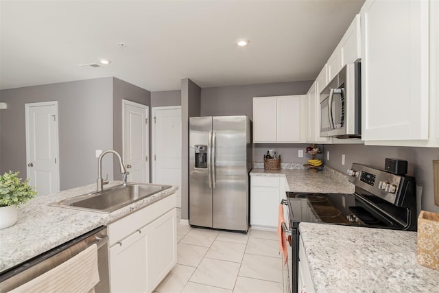 kitchen with sink, stainless steel appliances, white cabinets, and light stone countertops