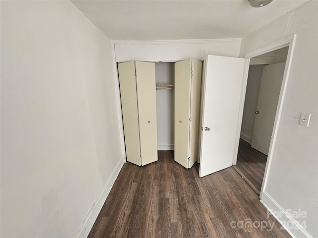 unfurnished bedroom with dark wood-type flooring and a closet