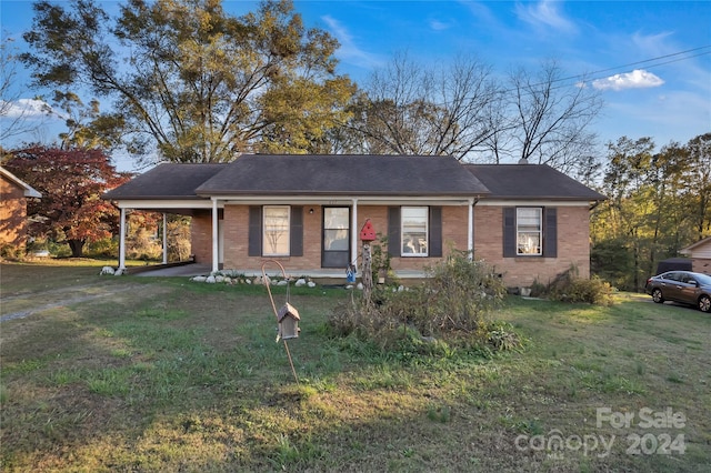 ranch-style home featuring a carport and a front lawn