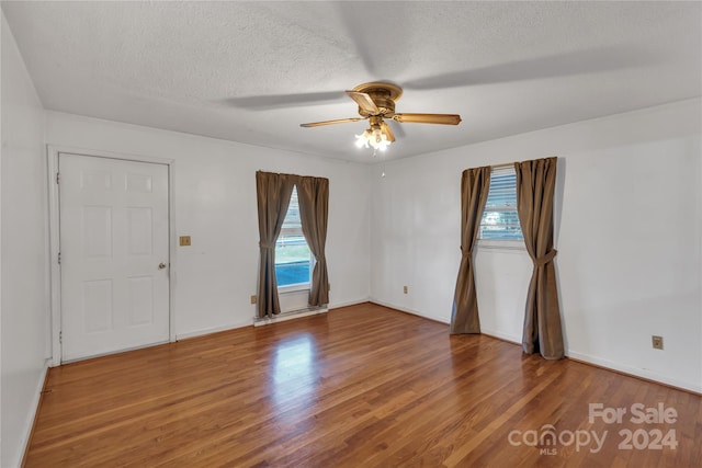 unfurnished room with hardwood / wood-style floors, a textured ceiling, and a wealth of natural light