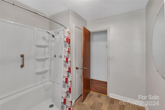 bathroom with a shower with curtain, wood-type flooring, and a textured ceiling