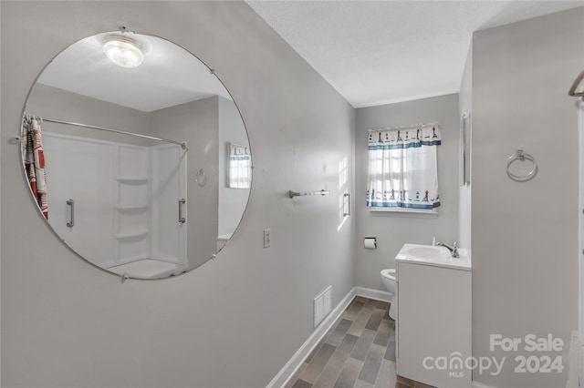 bathroom featuring wood-type flooring, vanity, toilet, and walk in shower