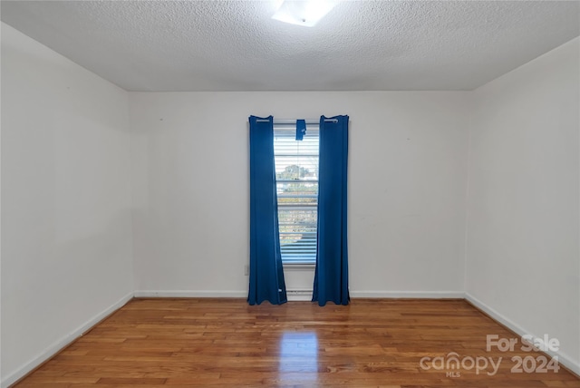 spare room with a textured ceiling and hardwood / wood-style flooring