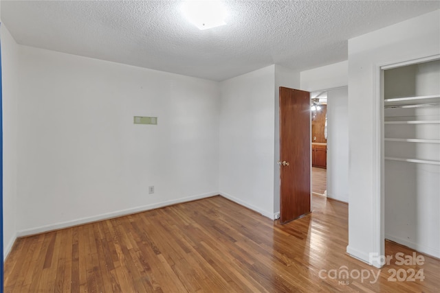 empty room with wood-type flooring and a textured ceiling