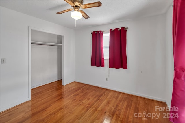 unfurnished bedroom with a textured ceiling, a closet, light hardwood / wood-style flooring, and ceiling fan