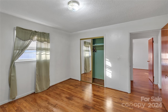 unfurnished bedroom featuring wood-type flooring, a textured ceiling, and a closet