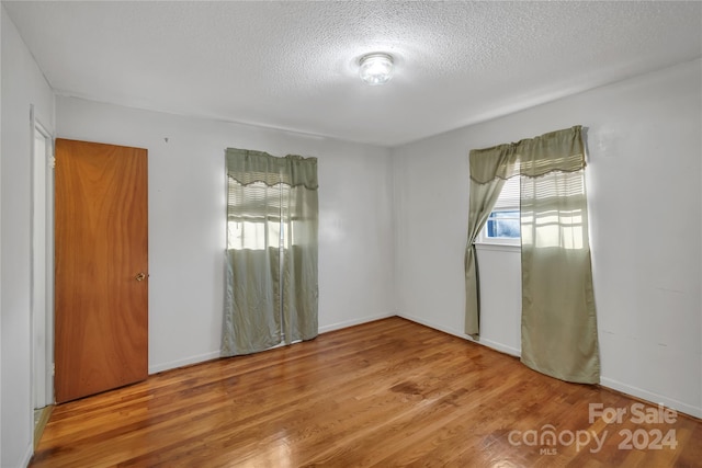 unfurnished room featuring hardwood / wood-style flooring and a textured ceiling