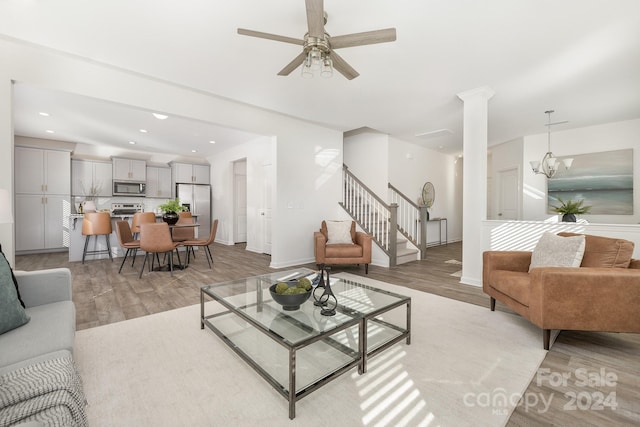 living room featuring ceiling fan with notable chandelier and light wood-type flooring