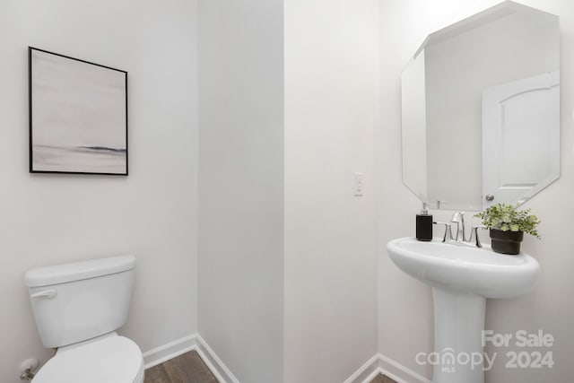 bathroom with hardwood / wood-style floors, toilet, and sink