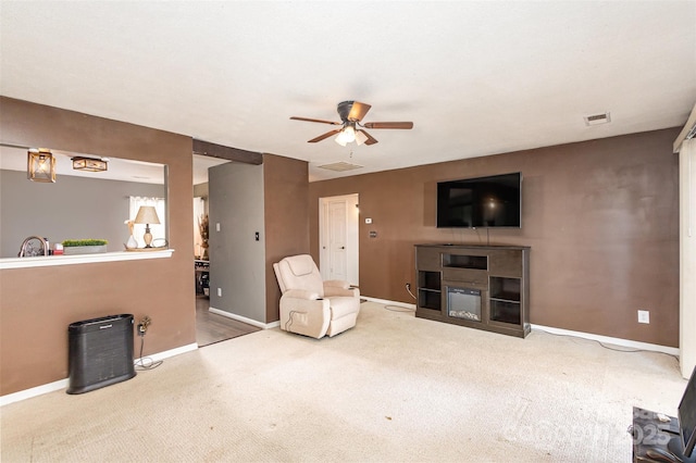 carpeted living room with ceiling fan and a fireplace